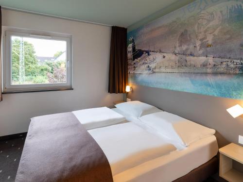 a hotel room with two beds and a window at B&B Hotel Koblenz in Koblenz