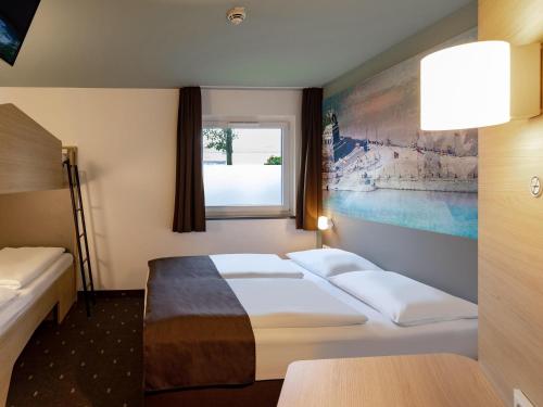 a hotel room with two beds and a window at B&B Hotel Koblenz in Koblenz