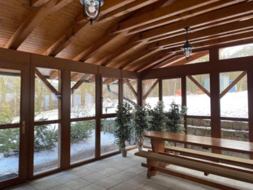 a wooden pavilion with a wooden bench and windows at Selský Dvůr Perštejn in Pürstein