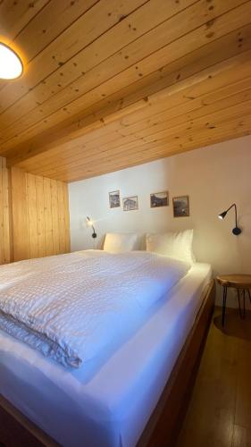 a large white bed in a room with wooden ceilings at Bergquelle 1.OG in Bettmeralp