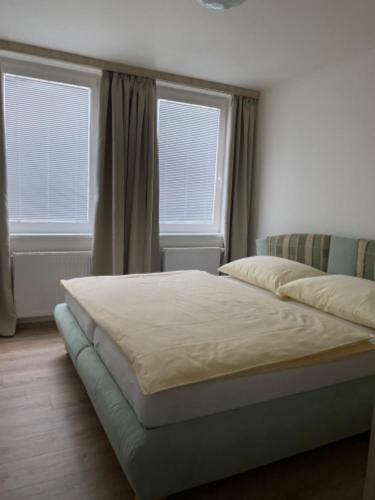a bed sitting in a room with two windows at Selský Dvůr Perštejn in Pürstein
