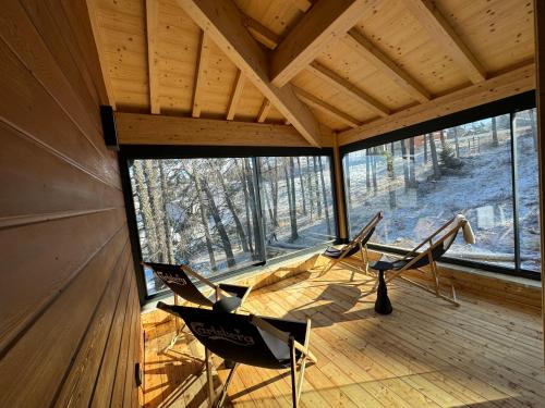 2 chaises assises sur une terrasse couverte dans une cabine dans l'établissement Chalet de luxe avec Sauna chez Papou, à Saint-Étienne-en-Dévoluy