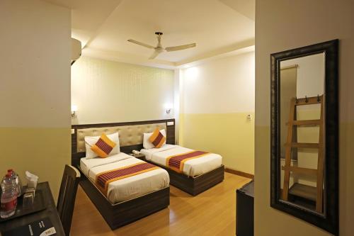 a hotel room with two beds and a mirror at Hotel Aeroporto Near By Delhi International Airport in New Delhi