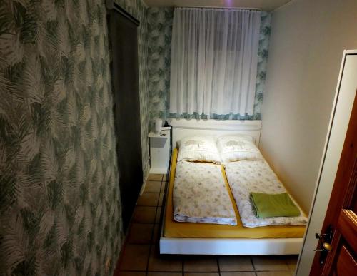 Cama pequeña en habitación pequeña con cortina en Ferienwohnung Hanne en Netphen