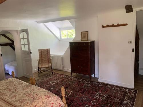 a bedroom with a bed and a chair and a window at Charmante maison dans le parc d'un château in Saint-Pierre-du-Val