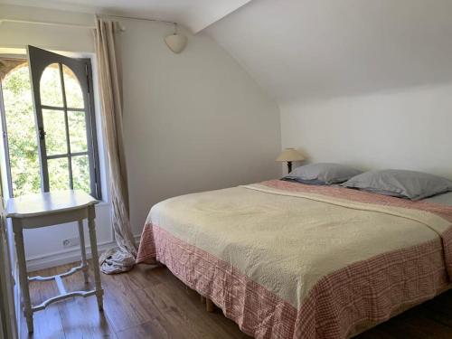 a bedroom with a bed and a table and a window at Charmante maison dans le parc d'un château in Saint-Pierre-du-Val