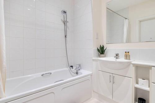 baño blanco con ducha y lavamanos en Pass the Keys Liberty House · Spacious modern apartment, en Chertsey