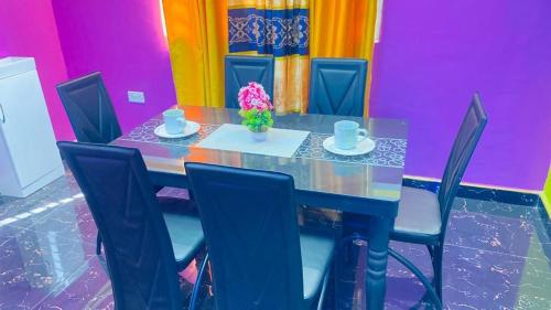 einem Esstisch mit Stühlen und einem Tisch mit Blumen darauf in der Unterkunft Favoured Apartment in Kwabenyan
