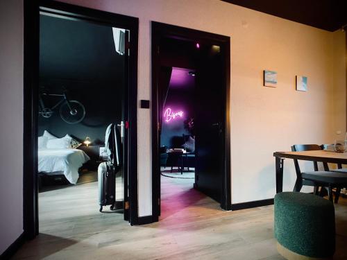 een kamer met een bed en een kamer met een bord waarop staat: verblijf bij Les Chambres @ BisousBisous in Jodoigne