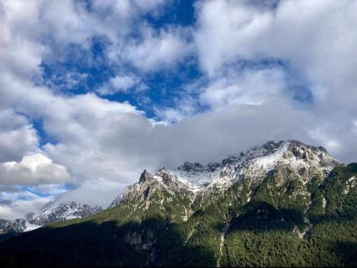 uma montanha coberta de neve e nuvens no céu em Sonnenhof em Mittenwald