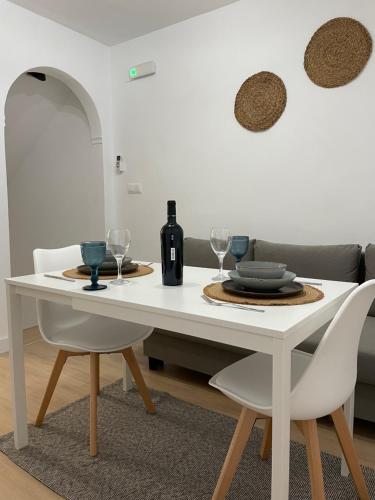 einen weißen Esstisch mit 2 Stühlen und eine Flasche Wein in der Unterkunft Mirador Templario in Jerez de los Caballeros