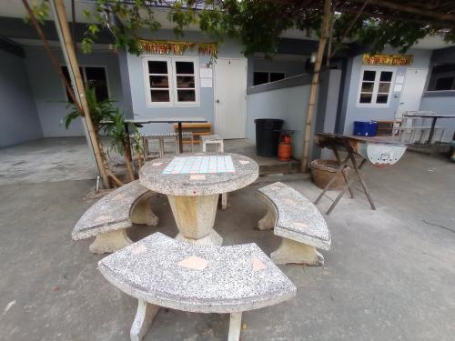 um grupo de mesas e bancos em frente a um edifício em บ้านพักมาซามิโฮม หาดเจ้าสำราญ Mazami Homes At Chao Samran Beach Phetchaburi em Ban Hat Cha Samran