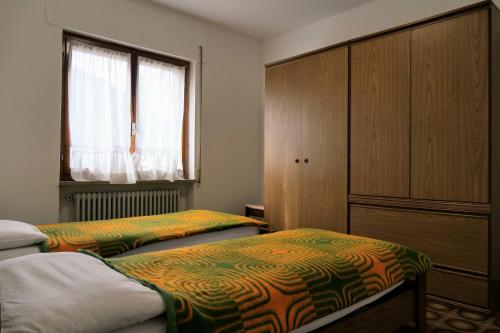 a bedroom with two beds and a cabinet and a window at Casa Ezio - Piano terra in Malesco