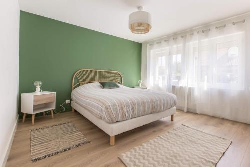 Un dormitorio con una cama y una pared verde. en Résidence Jaurès, en Marly