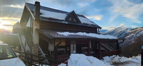 una baita di tronchi con neve sul tetto di Villa Green Park a Prizren