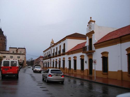 eine Stadtstraße mit Autos und ein Gebäude mit einem Uhrturm in der Unterkunft Humberto Apart A in Luján