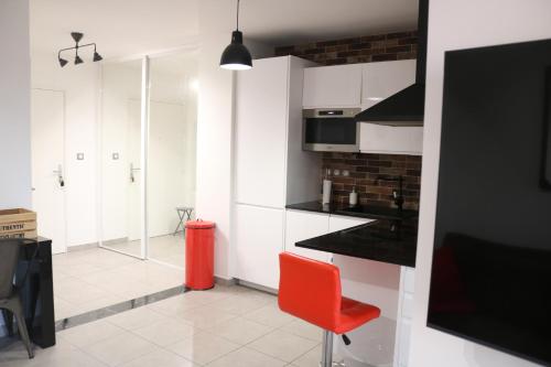 une cuisine avec des placards blancs et une chaise rouge dans l'établissement T2 moderne, vintage & cosy, à Sète