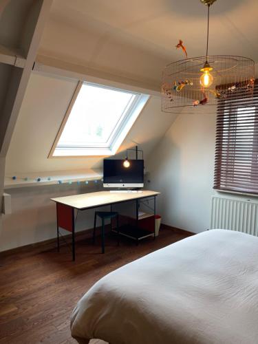 a bedroom with a bed and a desk with a television at Appartement aan prachtig rivierenlandschap in Temse