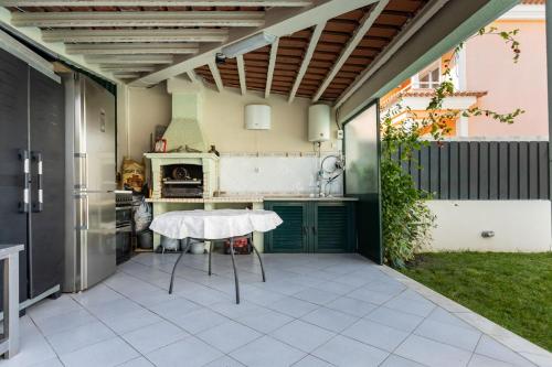 an outdoor patio with a table and a kitchen at Casa Ze da Cotta Marisol in Corroios