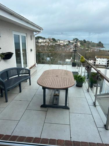 une table en bois sur un balcon avec une table et des bancs dans l'établissement Luxury 3 bedded room with sea peeps and parking, à Paignton