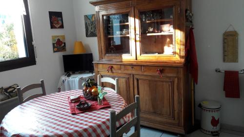 a dining room table with a wooden china cabinet and a table with a red at Appartement 3 étoiles avec jardin privatif et parking in Aix-les-Bains