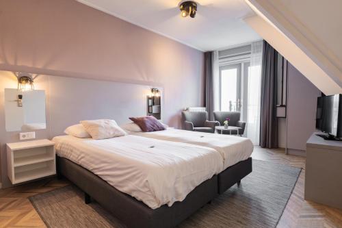een slaapkamer met een groot bed en een woonkamer bij Hotel In den Brouwery in Domburg