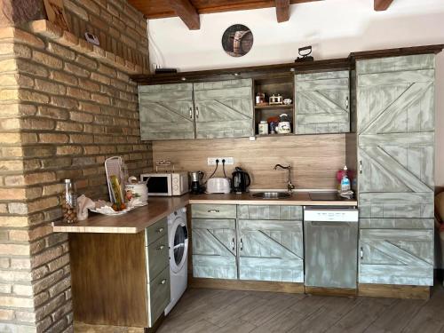 a kitchen with green cabinets and a brick wall at Kisdió Vendégház in Dég