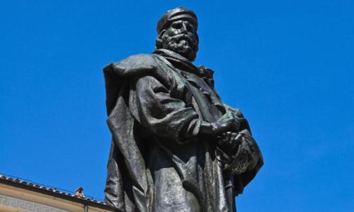 Una statua di un uomo in piedi di fronte a un edificio di residence a Parma