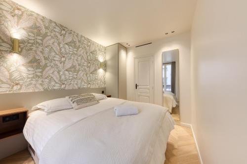 - une chambre avec un grand lit blanc orné d'une peinture murale dans l'établissement Les Reflets des Martyrs I 3CH I 2SDB I Clim, à Paris