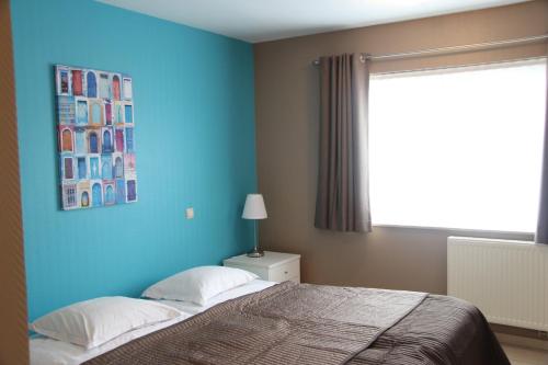 1 dormitorio con pared azul, cama y ventana en Relais Charlemagne Sca, en Herve