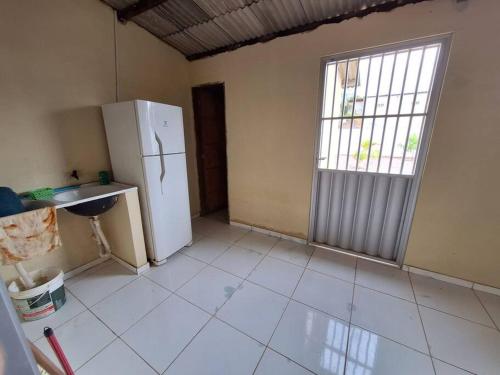 an empty kitchen with a refrigerator and a window at Casa de Avinha in Sirinhaém