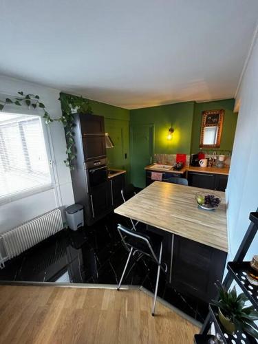 - une cuisine avec une table en bois et des murs verts dans l'établissement Appartement t2, à Vénissieux