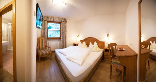 Habitación de hotel con cama, escritorio y habitación en Turmhotel Gschwendt, en Valle di Casies