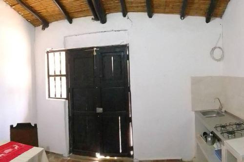 eine schwarze Tür in einer weißen Wand mit einem Fenster in der Unterkunft Departamento Raíces in Curití