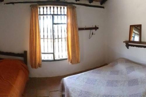 Schlafzimmer mit einem Bett und einem Fenster in der Unterkunft Departamento Raíces in Curití