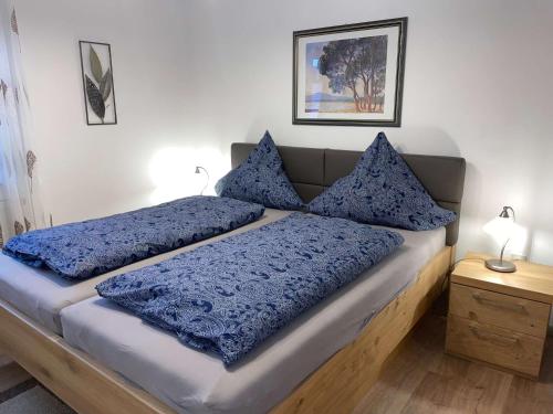 a bedroom with a bed with blue pillows on it at Einfach entspannen in Arrach