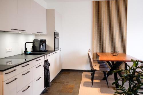 a kitchen with white cabinets and a wooden table at Trautesheim Ferienwohnungen in Wangen im Allgäu