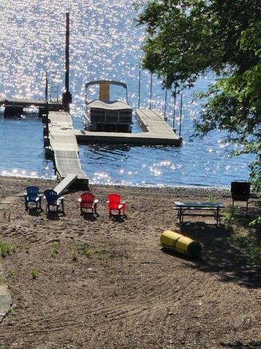 a dock with chairs and a table and a boat on the water at Spacious St Croix River Home with Private Beach in Lakeland