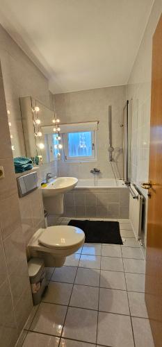 a bathroom with a sink and a toilet and a tub at An apartment located at nature with 2.5 rooms in Düsseldorf