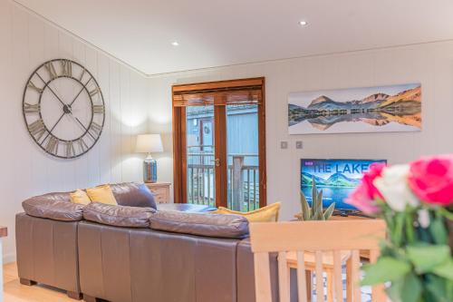 a living room with a couch and a clock on the wall at Family friendly, lovely Lakeland lodge with private parking and a patio in Hawkshead
