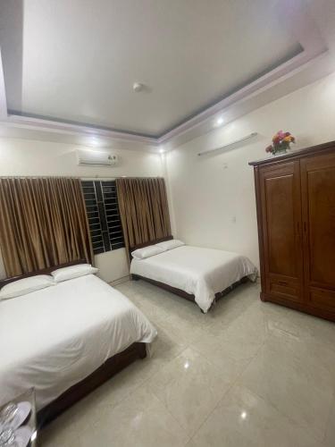 1 dormitorio con 2 camas y armario de madera en Holly's Hostel Ha Giang B&B, en Ha Giang