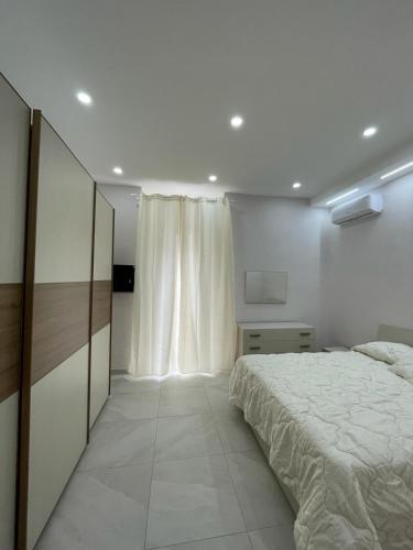 een witte slaapkamer met een bed en een televisie bij Ercolano Beautiful house in Ercolano