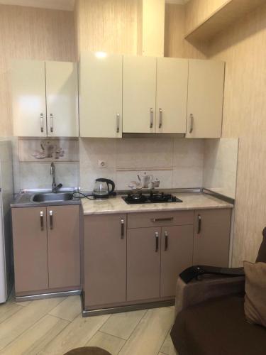 una cocina con armarios blancos y fregadero en Апартаменты в Тбилиси, en Tiflis