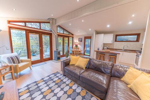 a living room with a leather couch and a kitchen at Family friendly, lovely Lakeland lodge with private parking and a patio in Hawkshead
