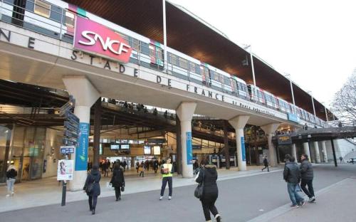 a group of people walking around a building with a train at Appartement avec Jardin - La Plaine Saint Denis in Saint-Denis
