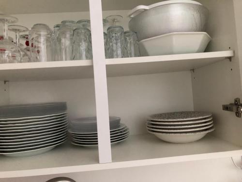 une étagère de cuisine avec des assiettes, des bols et des verres dans l'établissement Studio cabine en bord de mer, à La Grande-Motte, à La Grande Motte