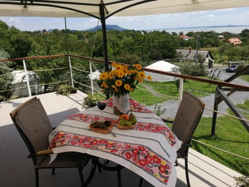 a table with a vase of flowers on a balcony at Jurta Hotel Balatongyörök in Balatongyörök