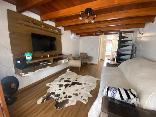 Habitación con cama, TV y sala de estar. en No mar, condomínio pé na areia, en Florianópolis