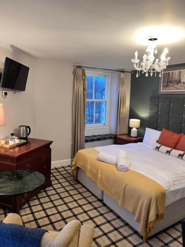 a bedroom with a bed and a desk and a tv at The Railway Hotel in Haydon Bridge