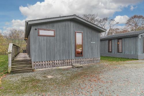 a gray tiny house with a staircase next to a building at Family friendly, lovely Lakeland lodge with private parking and a patio in Hawkshead